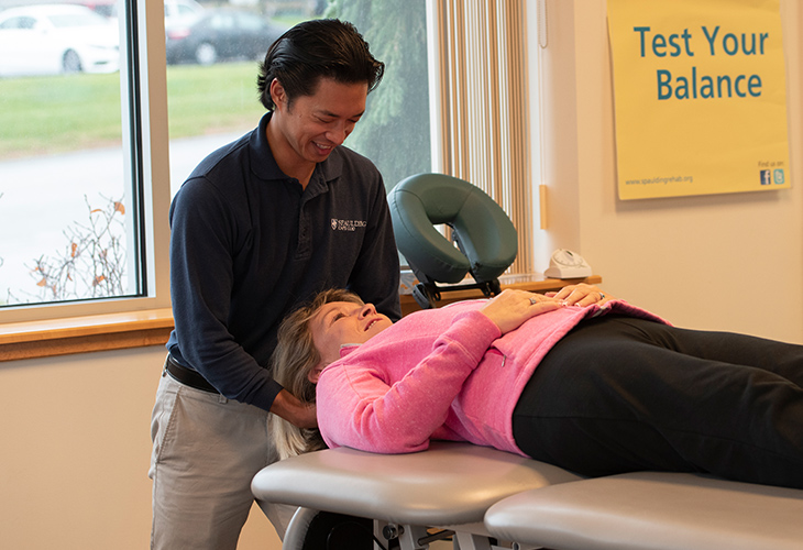 Plymouth team member supporting patient's head as they rehab