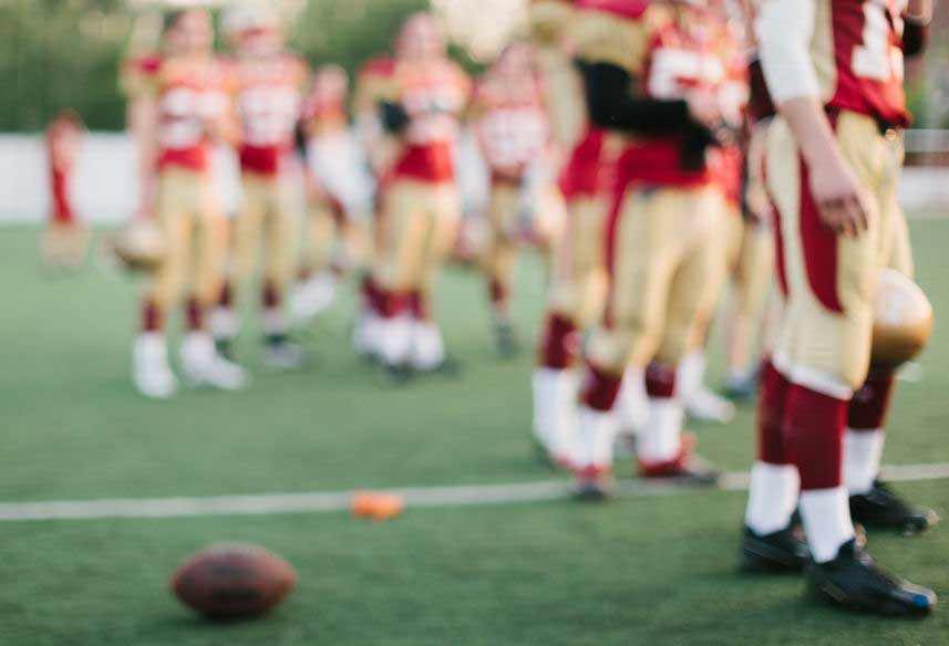 Football players standing on a field between plays.