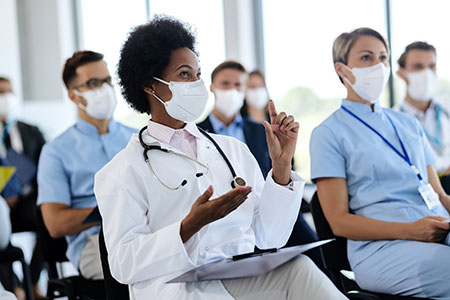 A Black female doctor speaks during a lecture.
