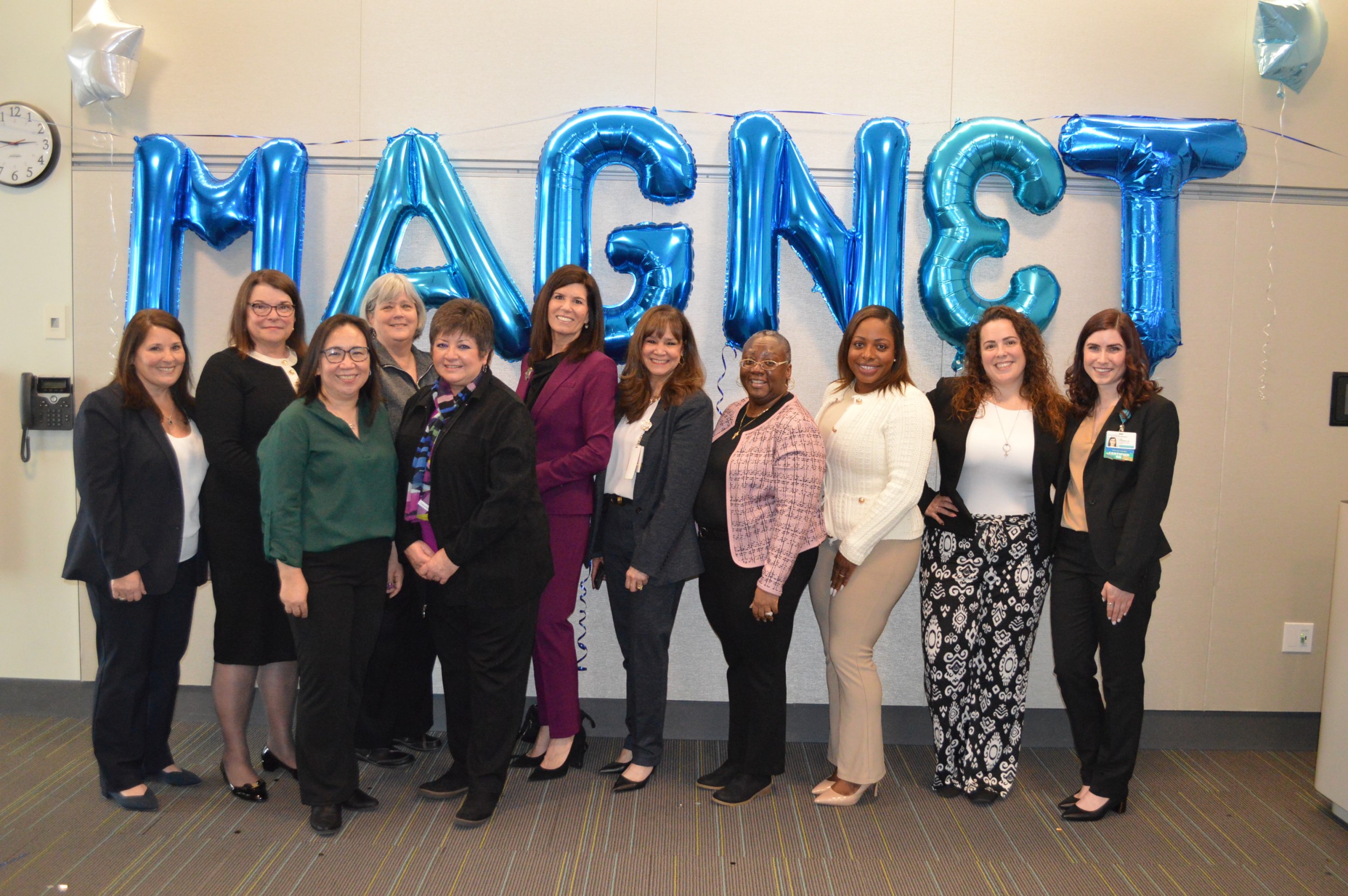 Group photo celebrating magnet status behind balloons that spell magnet