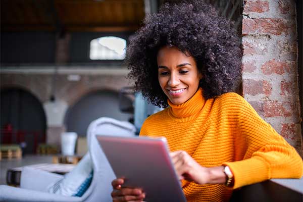 A smiling woman uses a tablet.