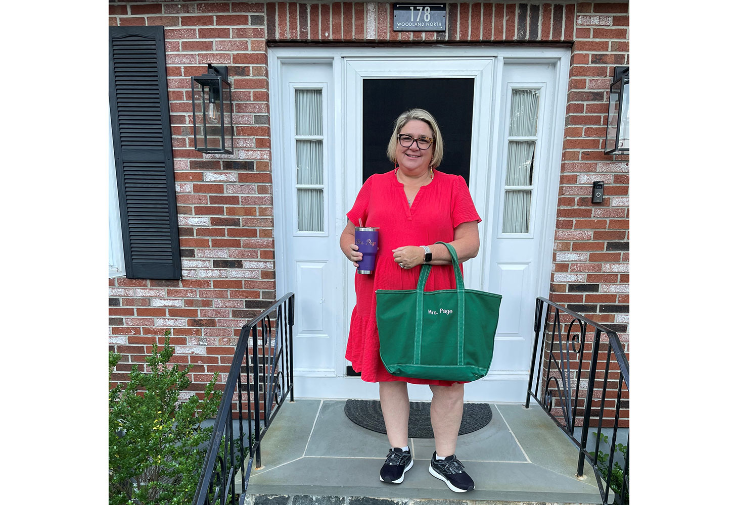 Kristin Page stands smiling on the front steps of her home.