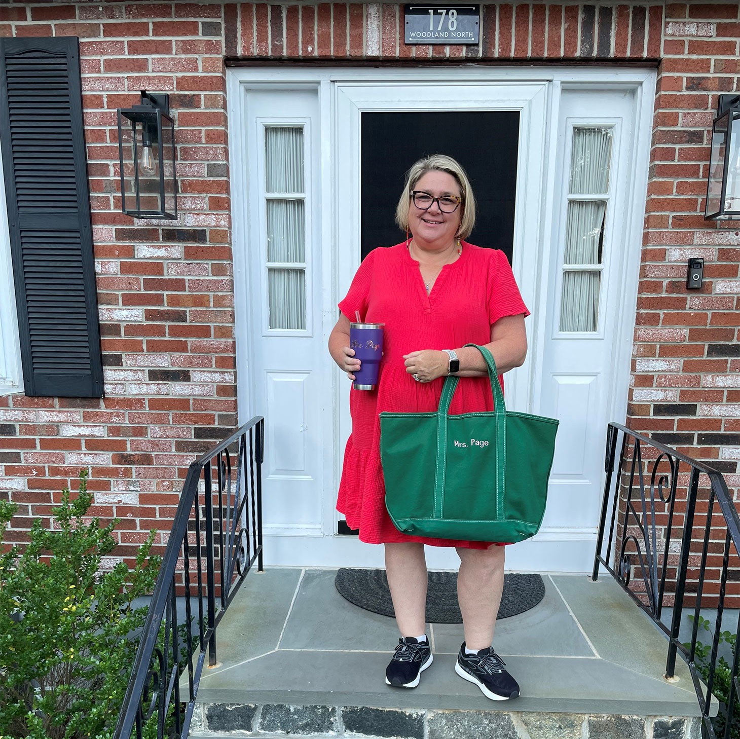 Kristin Page stands smiling on the front steps of her house.
