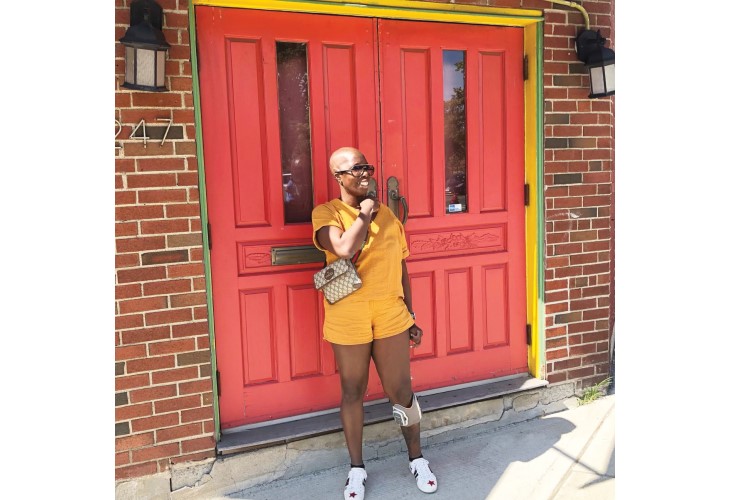 Lola smiling as she stands in front of her brightly painted front door.