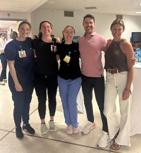 Sam, his wife Lauren, and three members of his rehab team wigth their arms around each others' shoulders.