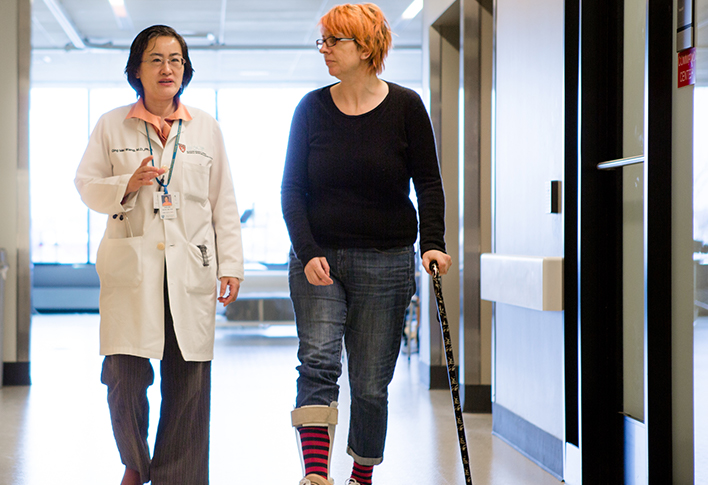 Nurse an dpatient with crutches walking through hallway