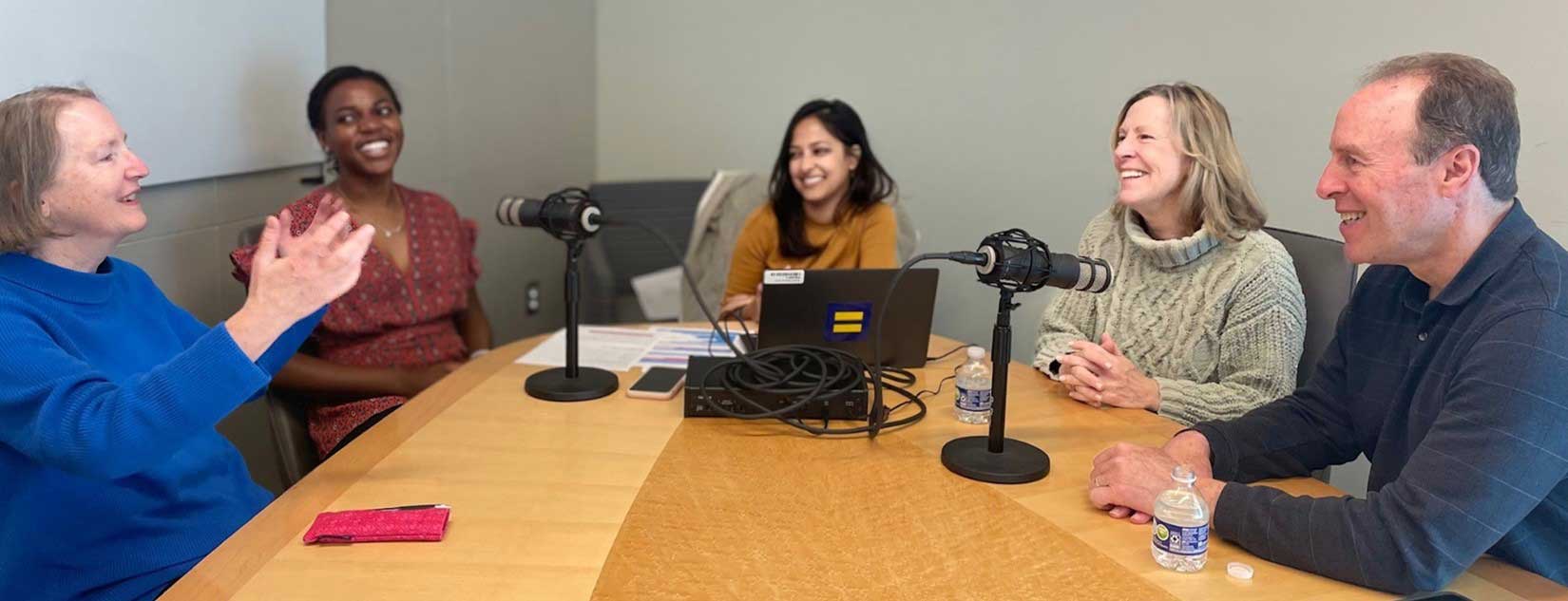 The panelists talking animatedly around a table during the podcast.